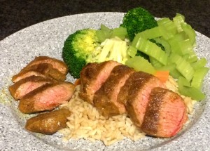 Picture of spiced lamb with brown rice and steamed green vegetables.
